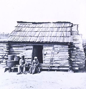 Slaves in front of a cabin.