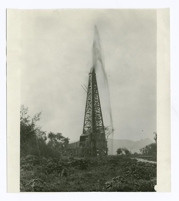 Oil well just completed. Picture shows crude oil flowing over the top of derrick before closing of valve which directs flow into tanks., Digital ID 111774, New York Public Library