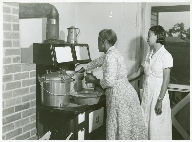 [Two African American women, Ada Turner and Evelyn M. Driver (Home Management and Home Economics Supervisor), canning English peas with pressure cooker in Mrs. Missouri Thomas' kitchen, Flint River Farms, Georgia, May 1939.],Ada Turner and Evelyn M. Driver Home Management and Home Economics Supervisor, canning English peas with pressure cooker in Mrs. Missouri Thomas' kitchen, Flint River Farms, Georgia, May 1939., Digital ID 1260005, New York Public Library