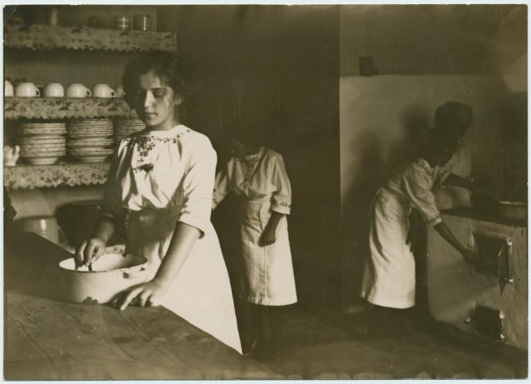 [Kitchen scene. Young woman in the foreground.], Digital ID 1536557, New York Public Library