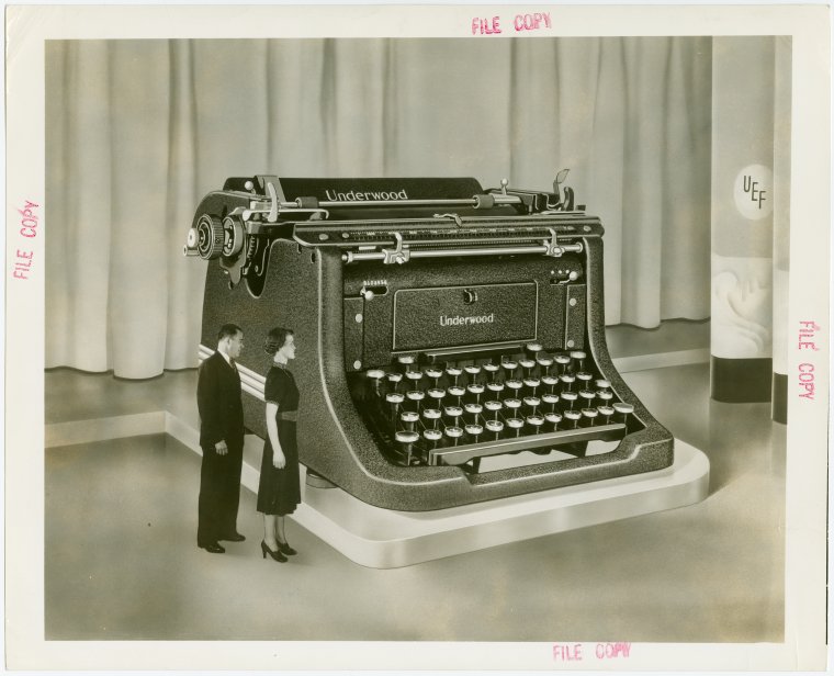 Underwood Elliott Fisher Co. - Man and woman posing with giant typewriter, Digital ID 1685575, New York Public Library