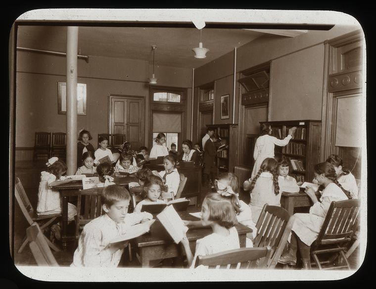  children at tables and choosing books from shelves, ca. 1920., Digital ID 465273, New York Public Library