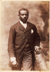Studio portrait of a man dressed in jacket, vest, tie and striped pants
