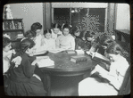 Tremont, interior view, girls gathered around table reading under guidance of "Miss Farren(?)"  "...ford Club,"