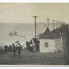 Midland Beach, Staten Island. [people on boardwalk, entrance building to pier, old utility poles, people on float in water.]
