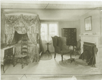 A New England bedroom of about 1800, showing four poster with curtains and valance, and truckle bed to be pulled out from beneath larger bed.