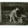 Digger is breaking large lumps of coal with an ax preparatory to loading the car. He uses an open flame lamp. Unsafe practice in gaseous mine.