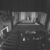 Rehearsal photo of "Marco Millions" (1928). Producer, Lawrence Langner, director, Philip Moeller, set designer, Lee Simonson, together with others (unidentified) of the Theater Guild staff witnessing from the orchestra an on stage rehearsal at Guild Theatre. (Note: Ph. Moeller, light suit, standing, L. Simonson, standing, arms crossed, L. Langer, seated, facing Simonson.)