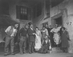 Scene in Catfish Row. Frank Wilson (Porgy, knees by steps), Georgette Harvey (Maria, in the door), Evelyn Ellis (Bess, extreme right), Wesley Hill (Jack, second from left).