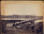 Pontoon bridge across the James [Men sitting and standing in foreground, ships at anchor in river] / Alexander Gardner