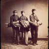 Lifting a wounded or sick soldier [Three soldiers carry a fourth to demonstrate one stage of the correct method to raise a soldier from a reclining position for carrying]