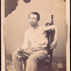 John F. Claghorn : 214 Gold St., Brooklyn L.I. [Man seated on chair, shirt partially removed to display wounded left arm resting over chair back]