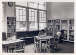 Seated reader and reader at bookshelves, Donnell-Nathan Strauss
