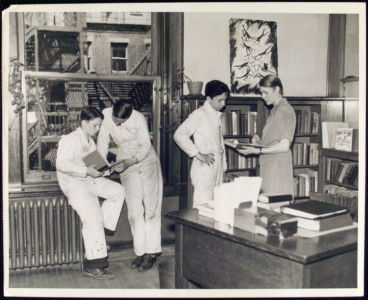 Margaret Scoggin and another librarian poring over books with two teenaged boys.