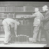 Three men at dusting books, one bent over