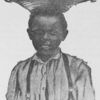 Young African-American boy carrying basket on his head.