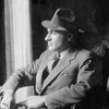 Jed Harris (in hat, seated in armchair, profile)