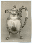 Silver pitcher decorated with grapes and leaves.