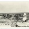 Soldiers carrying equipment past trenches