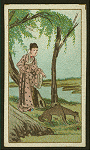 Woman feeds wild dog beside a river.