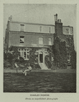 Charles Dickens reading in front of a house.