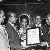 Group portrait showing Trinidad and Tobago political leader Sir Ellis E.I. Clarke receiving a Distinguished Service Citation from the Tobago Benevolent Association, in New York, circa 1970s