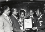 Group portrait showing Trinidad and Tobago political leader Sir Ellis E.I. Clarke receiving a Distinguished Service Citation from the Tobago Benevolent Association, in New York, circa 1970s