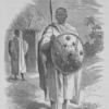 Male standing with spear and shield in hand, another man with spear and shield standing next to hut in background