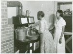 Ada Turner and Evelyn M. Driver Home Management and Home Economics Supervisor, canning English peas with pressure cooker in Mrs. Missouri Thomas' kitchen, Flint River Farms, Georgia, May 1939.