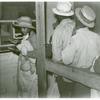 Negro day laborers brought in by truck from nearby towns, waiting to be paid off for cotton picking and buy supplies inside the plantation store, Friday night, Marcella Plantation, Mileston, Mississippi Delta, November 1939.