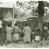 [African American women and children commemorating their lost relatives on their knees in a cemetery on All Saints' Day, 1938.]