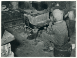 Negro boy sitting by the stove on a cold in the strawberry picking season near Independence, La. April 1939.