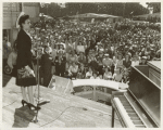 Lena Horne, African American actress, singer, and sponsor of the SS George Washington Carver, standing on stage and addressing a crowd at a war bond rally before the launching of the Liberty ship SS George Washington Carver
