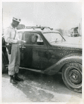 At a road block located near Viareggio, Private First Class George Weatheroy, Portland, Oregon, inspects tire certificate of an Italian driver