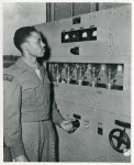 The first Negro soldier to be assigned to Armed Forces Network overseas, Pvt. Adolph Baxter, Jr., of Pontiac, Michigan, twirls a dial on a transmitter in Paris, France