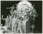 African American soldiers standing on the front of a stationary train and waving to the camera