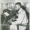 African American Private James C. Lee sitting at a teletype machine in the telegraph room at Camp Edwards, Kentucky