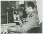 African American Master Sergeant William P. Thompkins sitting at a desk and looking at a photograph of his fiancée Delores Taylor, Fort Dix, New Jersey