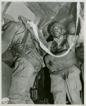 African American Staff Sergeant James O. Snowden wearing a parachute pack and waiting in line to jump out of a C-47 transport plane