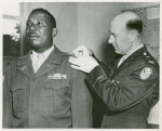 Colonel R. L. Salzmann pins a first Lieutenant's bar on the shoulder of African American Lieutenant Jesse J. Holbert