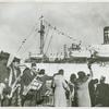 African American members of the 343rd ASF Band playing saxophones next to a crowd of women waving and welcoming the arrival of the last members of the 93rd Infantry Division