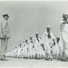 African American recruits in sailor uniforms walking in rows and passing in review before Lieutenant Commander Daniel W. Armstrong