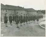 Army nurses standing at attention in front of their barracks and being inspected by staff officers, Army nurse training center, England