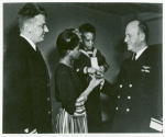 Mrs. Charles W. David, Jr.; African American widow and her three-year-old son, Neil Adrian receiving the Navy and Marine Corps Medal from Rear Admiral, Stanley V. Parker