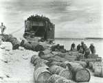 African American sailors rolling out barrels from a vessel to shore of Biak Islands