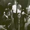 Four African American men singing with a conductor