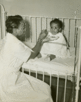 African American nurses' aide feeding an African American infant