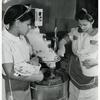 Female African American workers assisting each other at the dough mixer in food processing shop