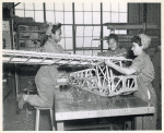 Three African American women constructing a wooden skeleton frame