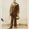 Full length portrait of man with bowler hat and cane.